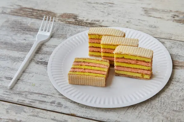 Beyaz tabakta katmanlı sünger keki, ahşap masada çatal, yakın plan meyve süngeri.