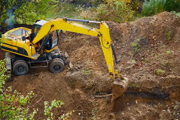 Kazı makinesi inşaat sahasındaki kazıyı doldurur., site çalışması ve temel çalışması, zemin çalışması; inşaat alanı ve mekanik çalışma; siteformasyon ve toprak taşımacılığı
