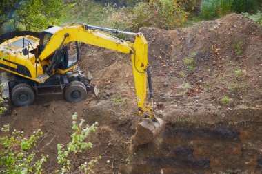 Kazı makinesi bir kova ile kazı yapıyor, kazı kovası inşaat alanında çalışıyor.