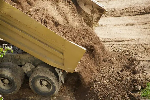 Toprak kamyon yatağından çarpıcı bir şekilde dışarı taşar.