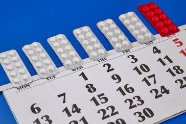 Haftanın günlerini kapsayan, hafta içi ve hafta sonlarını mavi arka planda geçiren ilaç paketleri. Sürekli ilaç alan, ilaçla yaşayan, tıbbi tedavi gören, ilaç almayı hatırlatan.