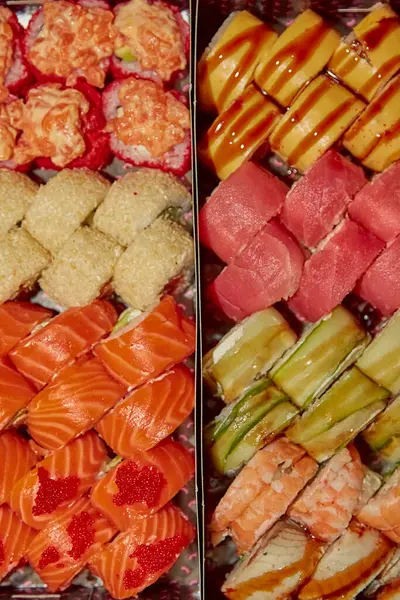 Philadelphia suşisi, sıcak ışıkta, bulanık bir şekilde siyah ambalaj kutularında yuvarlanıyor. Yumuşak, ılık ışıkta suşi, aşçılık sanatı malzemelerin dokusunu ve detaylarını gözler önüne seriyor..