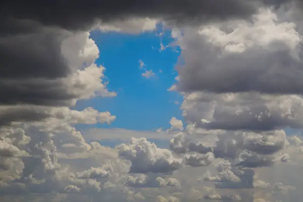 Küçük bir mavi gökyüzü parçası kara bulutların arasından gözetliyor. Stratocumulus ve cavum, meteorolojik fenomen, meteorolojik olay