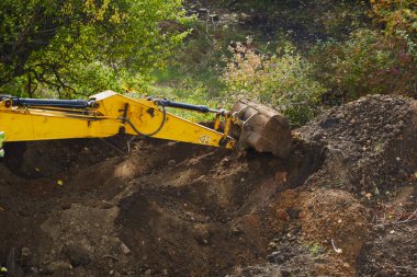 Kazıcının kovası toprağı parçalayıp sert toprak ve kayaları parçaladı.
