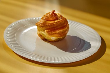 Beyaz bir tabakta, sarı bir zemine karşı beyaz bir tatlı, porsiyonlu tatlı sunumu. 