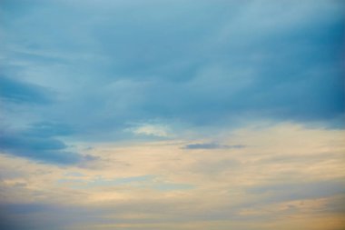 Mavi bulutlar üzerinde batan güneşin yumuşak sarı güneş ışığı, akşam gökyüzünün pastel tonları, gün batımı bulutları ile gökyüzü manzarası