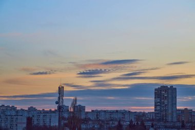 Alacakaranlık şehrinin üzerinde güneşle aydınlanan akşam gökyüzü ışıksız.