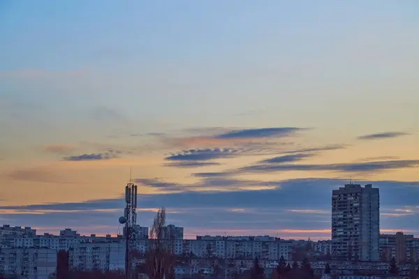 Alacakaranlık şehrinin üzerinde güneşle aydınlanan akşam gökyüzü ışıksız.
