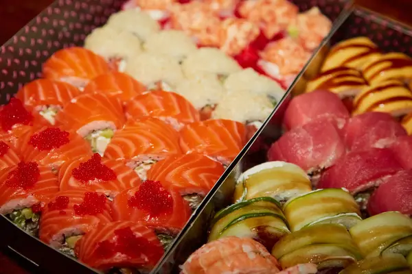 Suşi Philadelphia 'ya yakın çekim yapar. Siyah kutular içinde. Sıcak ışık altında. Arka plan bulanık. 