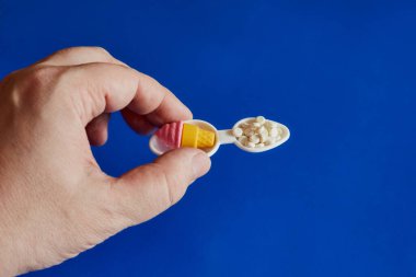 Bir yanda dondurma, diğer yanda dondurma, mavi arka plan, diyabet tedavisi, obezite tedavisi, diyet kontrolü olan çift ölçü kaşığında bir porsiyon dondurma tutan bir el.. 