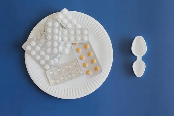 Su toplayan haplarla dolu bir tepsi ve yanında bir ölçü kaşığı, tıbbi diyet, yüksek dozda ilaç, terapötik beslenme....