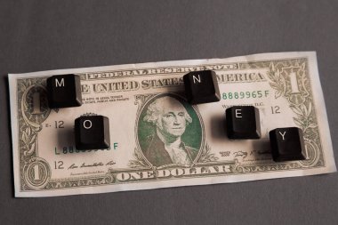 M, O, N, E, Y harfli bilgisayar anahtarları bir dolarlık banknotun üzerinde gri bir arkaplanla sanal para kazanıyorlar, mektuplardan 