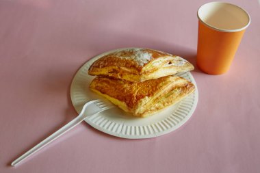 Pembe arka planda, tek kullanımlık bir tabakta, çatallı, tek kullanımlık, pembe arka planda, yakın planda, puf böreği üçgenleri. Fast food, sokak yemeği