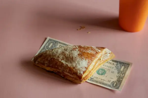Pembe arka planda puf böreği üçgeni ve bir dolar, ucuz yemek, indirimli yemek, sokak yemeği.