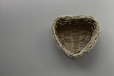 Gri bir arka planda gri dokuma kalp şeklinde sepet, duyguların ve aşkın yokluğu, yalnızlık veya belirsizlik hissi..