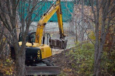 Toprak işlerinde eski bir beton paneli kaldıran bir kazıcı, bir inşaat alanında kazıcı işi.