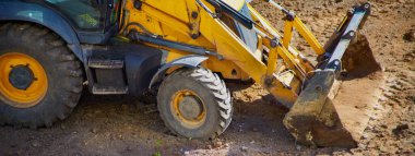 Bir buldozerin, inşaat için hazırlanan, bölgeyi temizleyen, işe başlayan, kirli bir alanda çalışan sarı kısmının yakın çekimi.