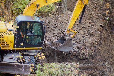 Yakın planda bir inşaat alanında siper kazan bir kazıcı, kazıcının toprak işleri, kazıcı vakıf için bir çukur kazıyor..
