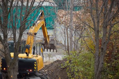 İnşaat alanındaki kazıcı temel çalışmaları için bir çukur kazıyor..