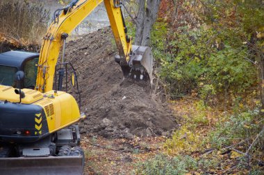 İnşaat alanındaki makineler: kazıcı temel çalışması için toprağı kazar.