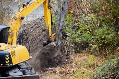Kazıcı inşaat alanındaki toprağı dikkatlice hareket ettiriyor..
