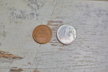 Bir sentlik ve bir rublelik sikkeler, yıpranmış bir masa üstü yüzeyi, makro çekim, bulanık arka plan, rubledeki değer kaybı, Rus para biriminin enflasyonu, Rusya 'da bir rubleden fazla eden bir sent, enflasyon