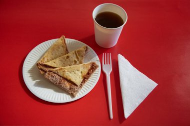 Bir fincan kahve, çatal ve peçetenin yanında şeker ve tarçınlı taze fırınlanmış tortilla cipsi kırmızı arka planda, yakın planda..
