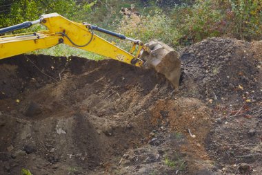 Kazıcının kovası toprağı kazar, siperler ve delikler oluşturur..