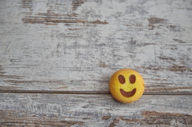 Ahşap bir masada tek bir gülen surat kurabiyesi. Model, iyi ruh hali, mutluluk ve neşe için yeri var. Ev konforu..