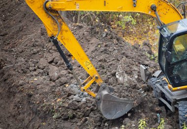 The excavator in the process of excavating soil at a construction site.