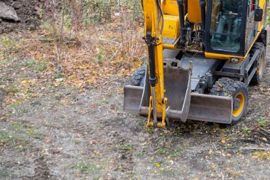 Sonbahar manzarasına karşı kovası olan büyük sarı bir inşaat kazıcısı çalışmaya hazır..