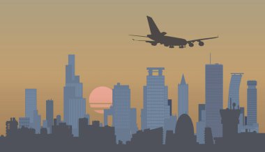 Uçak bir metropolün, gökdelenlerin ve gün batımının önünde uçuyor..