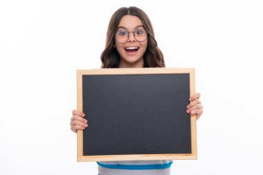 Beyaz bir stüdyoda izole edilmiş mesaj için elinde boş karatahta tutan genç bir çocuk. Boş yazı tahtası, kopyalama alanı. Mutlu kız yüzü, pozitif ve gülümseyen duygular