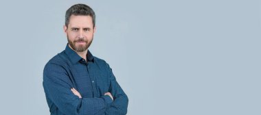 Sıradan tişörtlü sakallı adam kollarını çapraz tutuyor. Kendine güveni gri, rahat. İnsan yüzü portresi, kopyalama alanı olan pankart