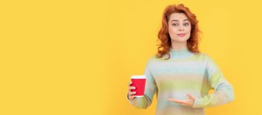 İzole edilmiş yüz portresi, fotokopi alanı olan pankart. Mutlu kızıl saçlı kadın kahve bardağının içinde kahve içmenin ürününü sunuyor.