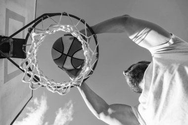 Profesyonel basketbolcu dışarıda antrenman yapıyor. Adamın spor motivasyonu var. Spor ve hobi. Sepete smaç bas. Smaç basıldı. Yaz etkinliği. Basketbol topu olan olgun bir adam..