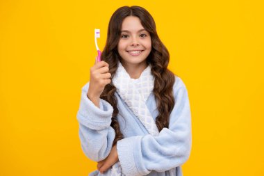 Kafkasyalı genç kızın portresi diş fırçası tutuyor, dişlerini fırçalıyor, sabah rutini, diş hijyeni, sarı arka planda izole edilmiş.