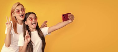 Anne ve kız çocuk afişi, kopyalama alanı, izole edilmiş arka plan. Mutlu kadın ve kız akıllı telefonla selfie çekiyorlar. Selfie ailesi. Modern hayat. mobil teknoloji