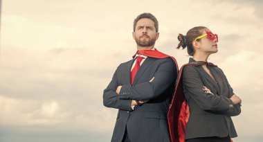 Gökyüzü geçmişinde süper kahraman kıyafetli bir iş çifti. motivasyon.