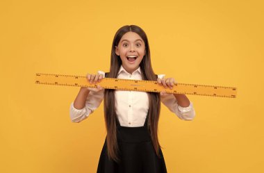 Okul üniformalı hayret bir çocuk matematik kurallarını ölçmek ve eğitim için elinde tutuyor..