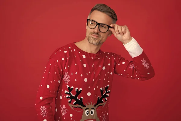 cheerful man in winter sweater and glasses. xmas guy on red background. happy new year. merry christmas.