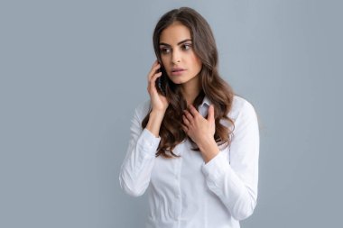 Akıllı telefonu olan ciddi bir kadın. Cep telefonu olan genç bir kadın. Gri arka planda akıllı telefonu olan bir iş kadını