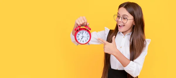 punctual teen girl checking time. happy nerd child pointing finger on alarm clock. Teenager child with clock alarm, horizontal poster. Banner header, copy space