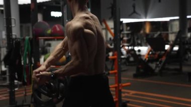 Spor salonundaki kaslı sporcunun arka görünüşü kara mayını egzersizi yapıyor. Spor salonundaki halter mayınlı sporcu. Spor salonunda halter ekipmanlı sporcu..