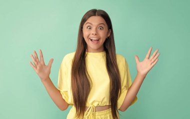 Güzellik ve moda. Kadın manken. Genç bir kızın güzel görünüşü. Mavi arka planda çocuk portresi. Olumlu duygularını ifade et. Uzun saçlı, şaşkın bir çocuk..