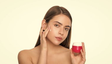 Beyaz arka planda izole edilmiş cilt kremi süren genç bir bayan, günlük alışkanlık..