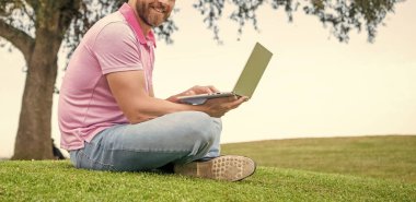 Kesilmiş gülen adam e-postayı kontrol et. Serbest çalışan adam internette çim üzerinde oturuyor. İnternette yazıyorum. İş adamı blog yazmak için dizüstü bilgisayar kullanıyor. Sosyal ağ ve web günlüğü. modern iş bilgisayar iletişimi.