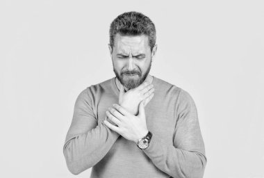 Sakallı olgun bir adam gri arka planda boğaz ağrısı çekiyor, soğuk..