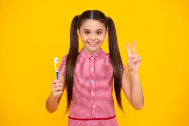 Kafkasyalı genç kızın portresi diş fırçası tutuyor, dişlerini fırçalıyor, sabah rutini, diş hijyeni, sarı arka planda izole edilmiş. Mutlu ergen, pozitif ve gülümseyen genç kız duyguları