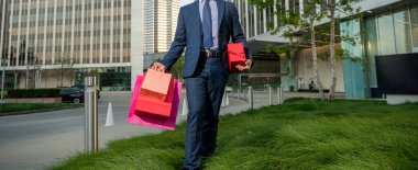 Takım elbiseli işadamı paketlerini ve hediye kutusunu ofisin dışında gezdiriyor, kadınlar günü..